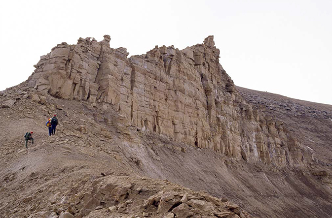 Fig. 35 Type section of the Pelion Formation. Persons for scale. Pelion, central Jameson Land (Figs 1, 2a). The vertical sandstone cliff immediately above the geologists is c. 10 m high.