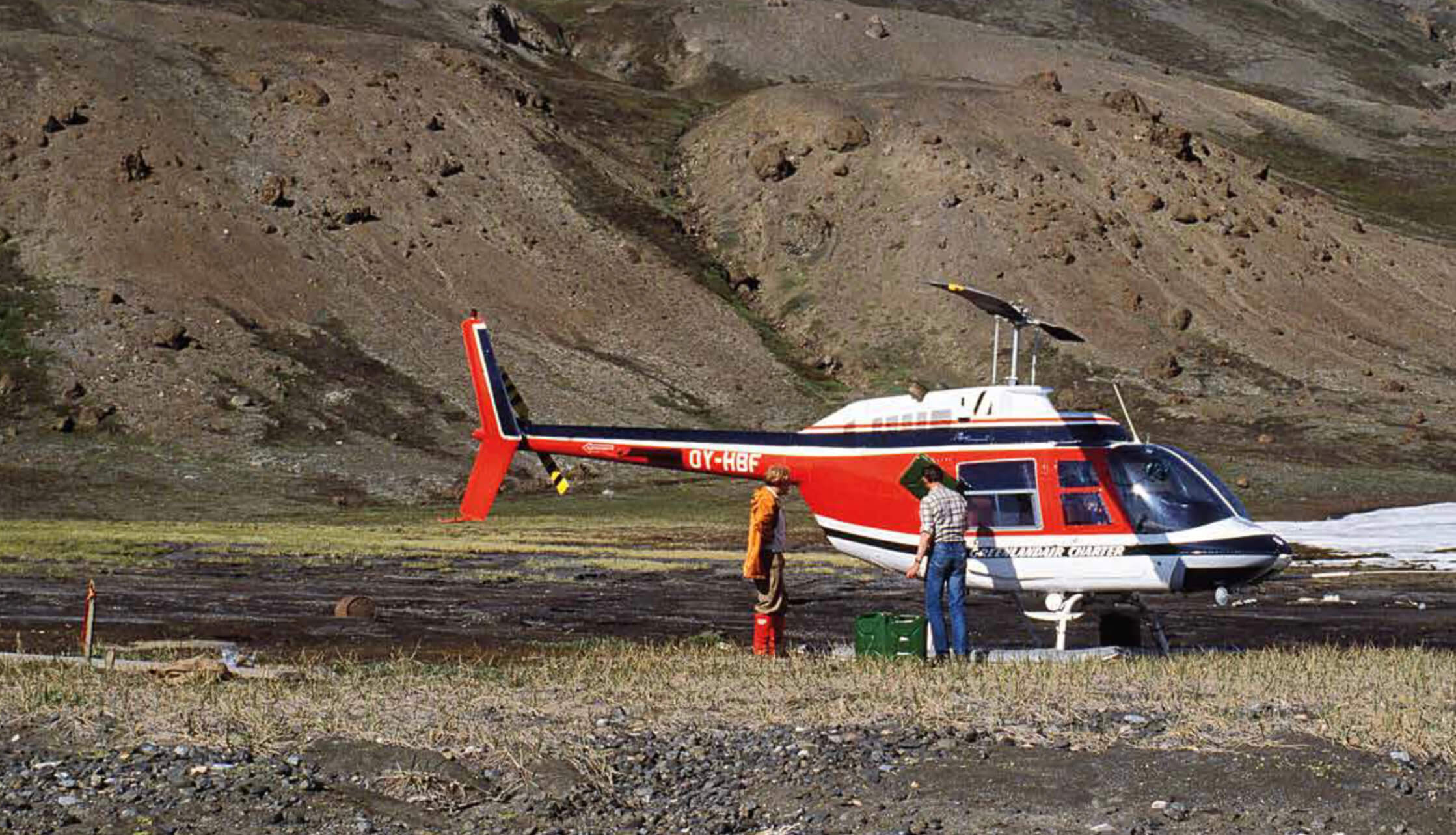 Men next to helicopter with mountain slopes in background