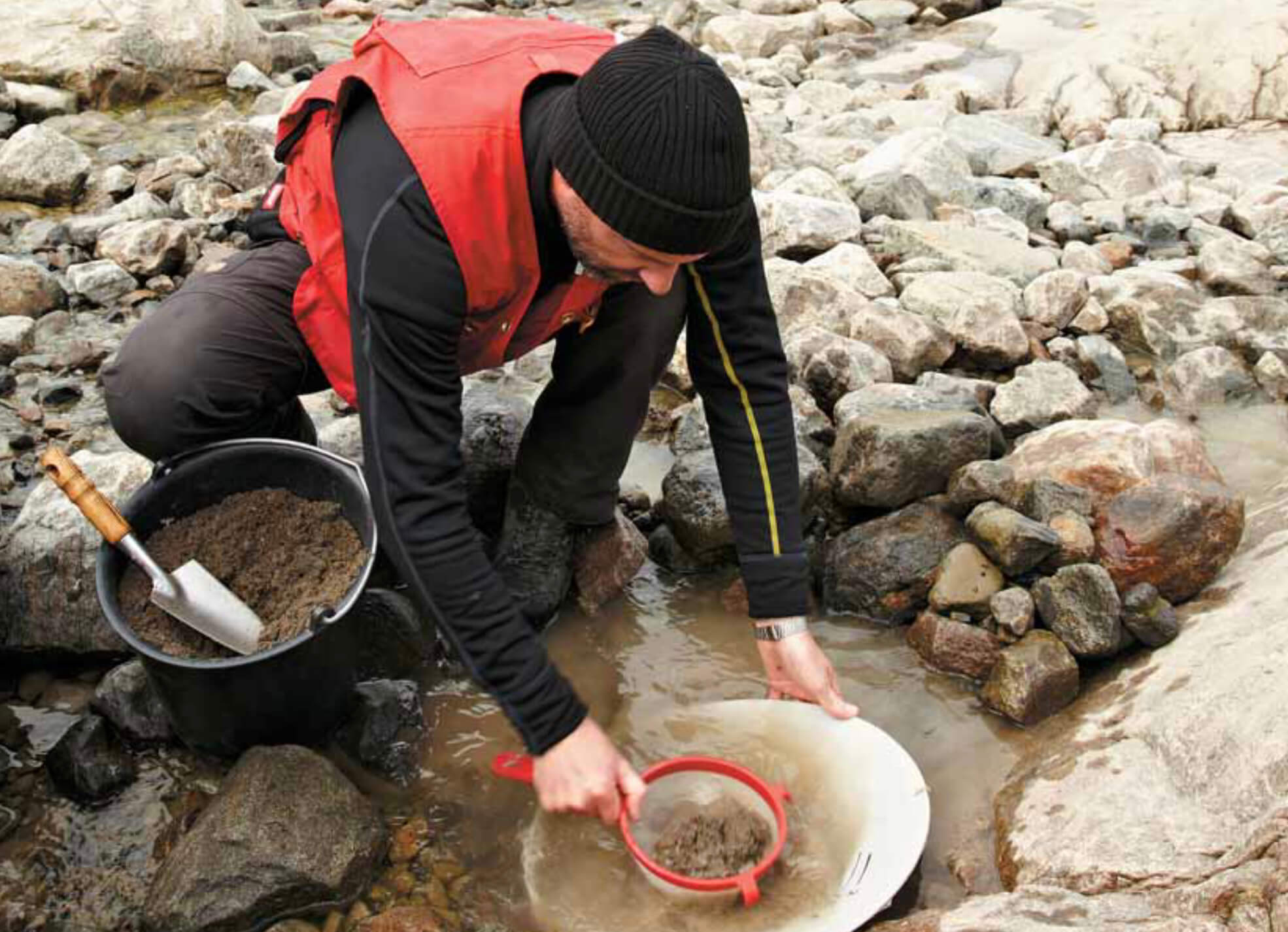 Person crouching by a stream.