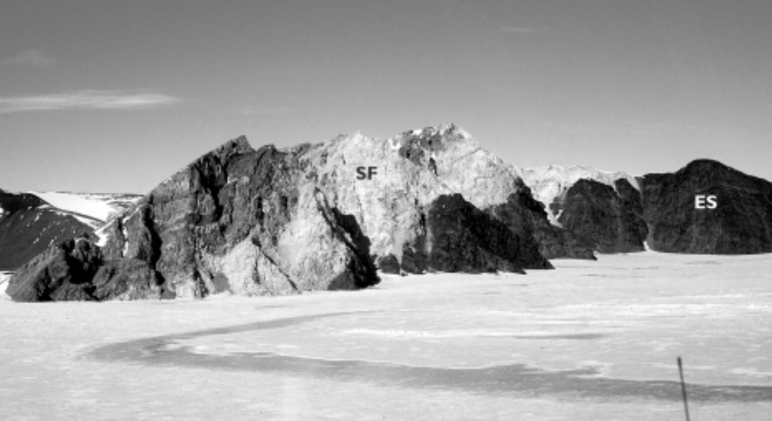 Black and white photo of mountains with ice in the foreground.