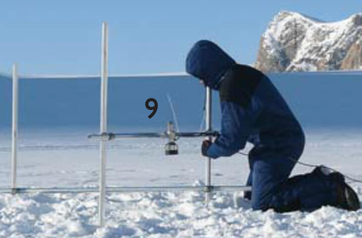 A person fixes monitoring equipment on the ice sheet.