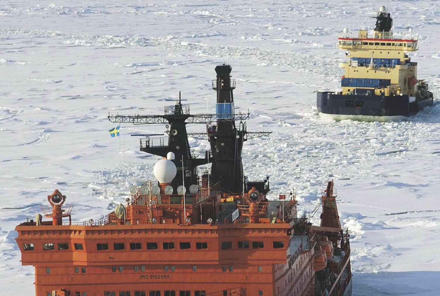 A research vessel with pilot vessel make their way through sea ice.