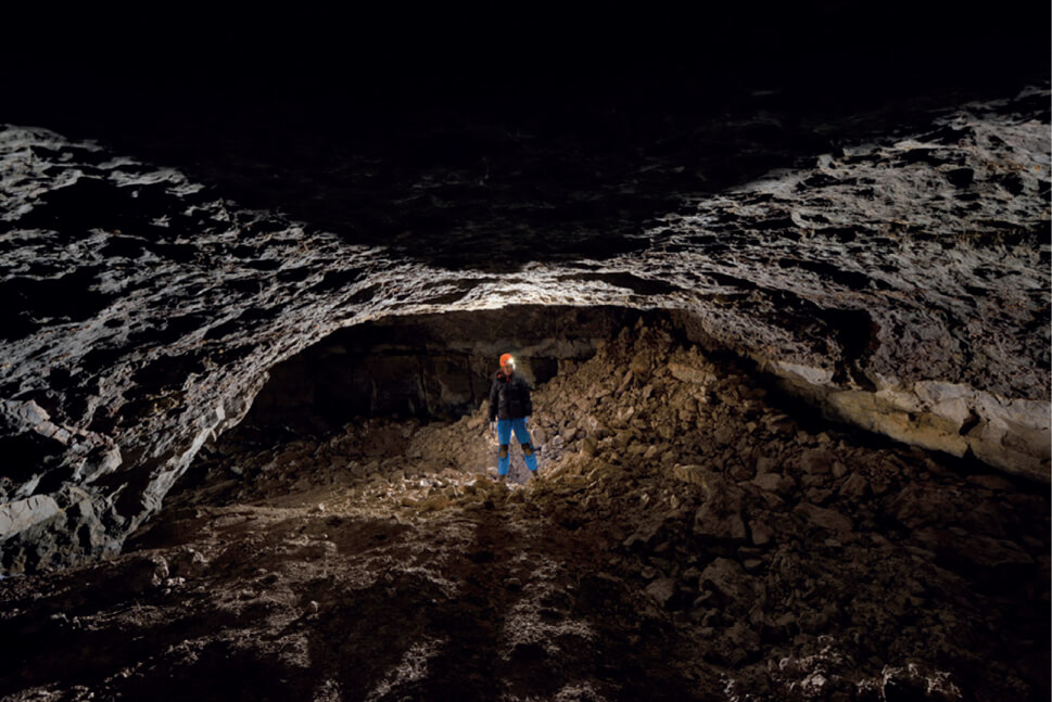 Photo of a person standing inside a cave